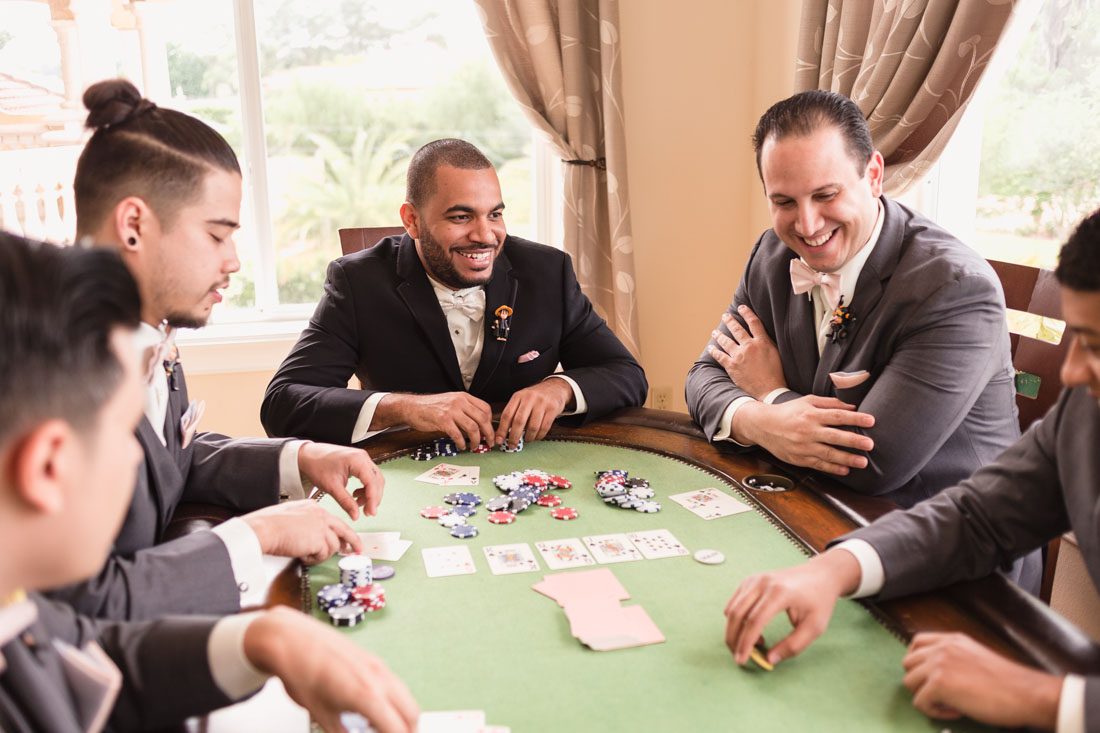 Groomsmen playing poker before wedding at Crystal Ballroom veranda by top Orlando wedding photographer