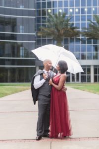 Couple poses with an umbrella during rain at their engagement session