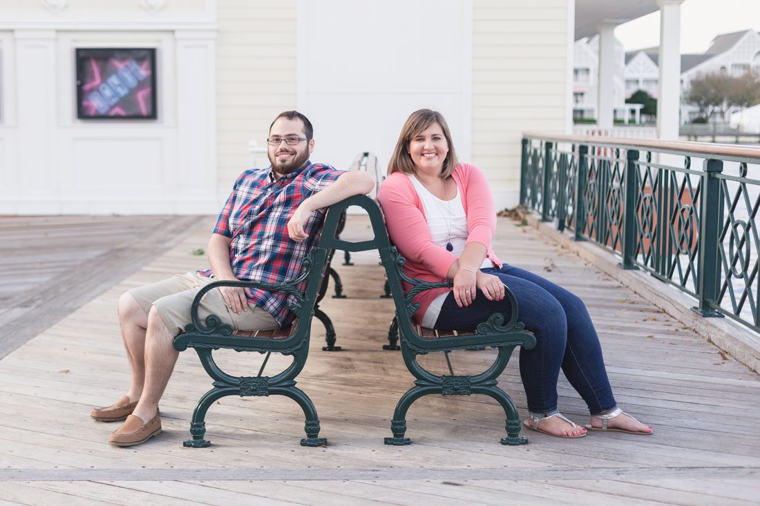Newly engaged couple sitting on a bench for their engagement photography session at Disney Boardwalk