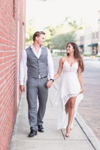Engaged couple walks along a red brick wall in historic Winter Garden just west of Orlando during their engagement photography shoot