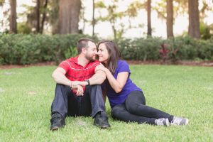 Couple sitting in the grass at their park engagement session at Kraft Azalea gardens captured by top Orlando wedding photographer and videographer