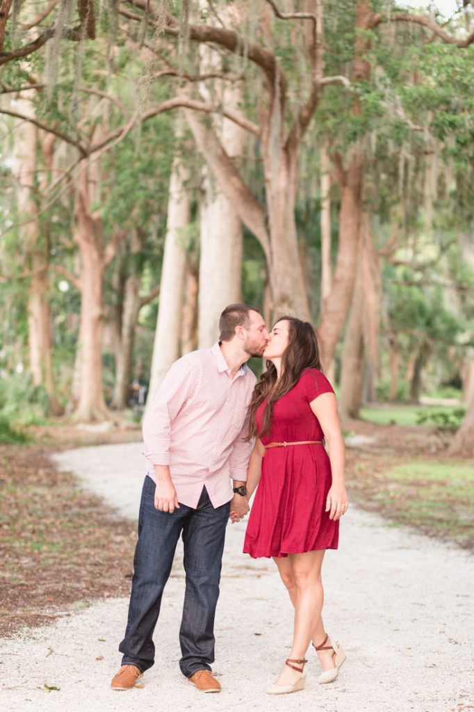 Couple walking through tree lined path at Kraft Azalea gardens for their engagement session with Orlando wedding photographer and videographer
