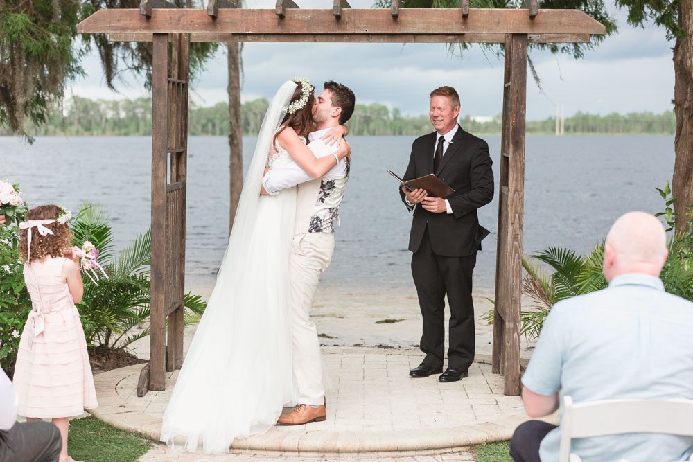 The bride and groom share their first kiss during their wedding ceremony at Paradise Cove Orlanod