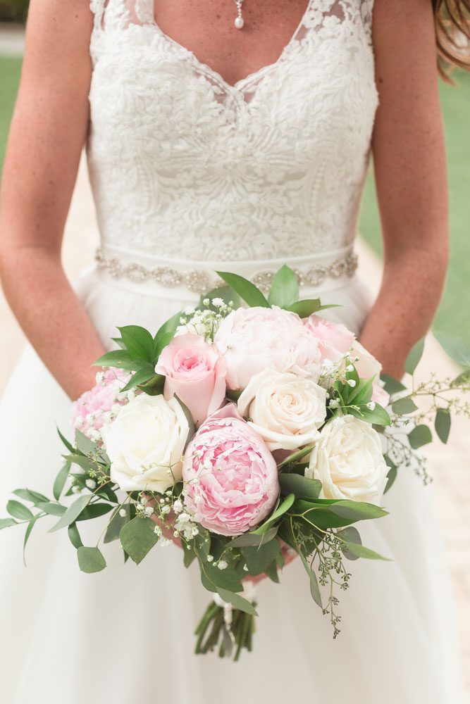 Orlando wedding photographer captures bride holding her beautiful blush pink and cream bouquet at Paradise Cove