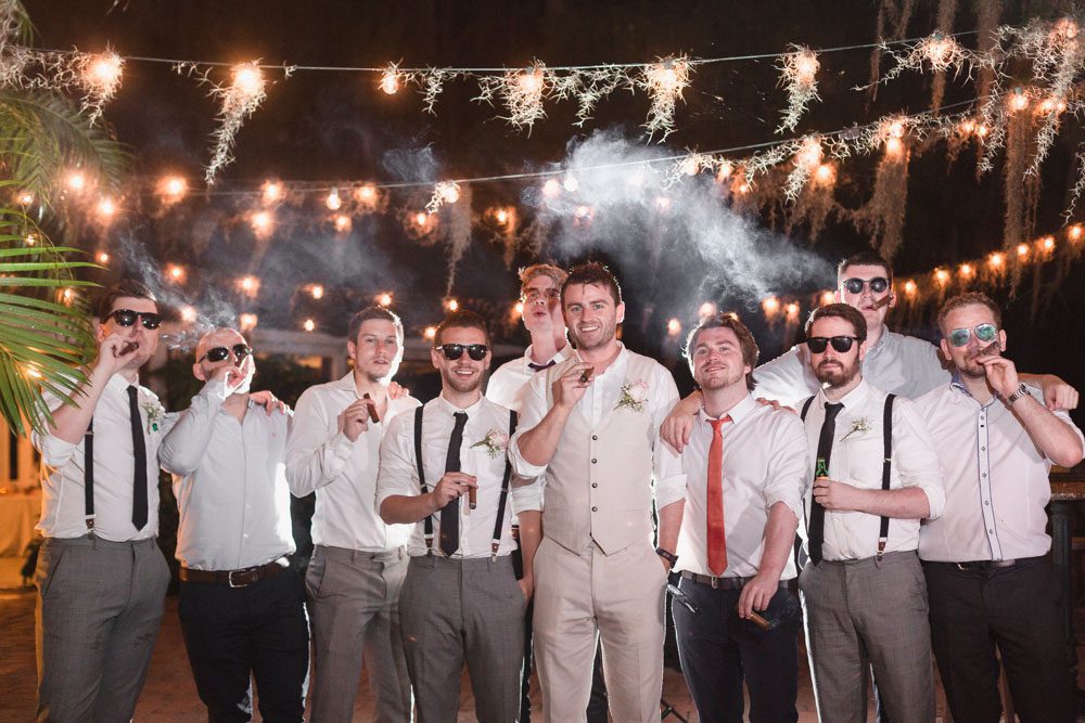 Groom smoking cigars with his groomsmen at his Paradise Cove Orlando wedding day