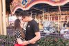 Married couple kisses in front of the spinning carousel for a creative anniversary engagement session photo at Disney