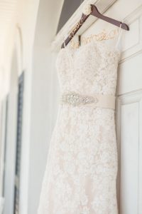 Brides wedding dress hanging in a doorway for a rustic chic country wedding at a barn captured by Orlando wedding photographer and videographer