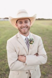 Groom wearing his cowboy hat and a tan suit for his country rustic wedding day at a barn north of Orlando