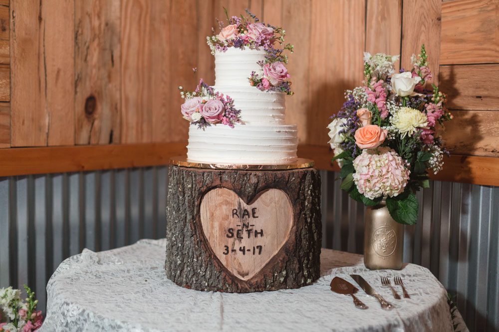 Rustic country wedding cake with buttercream on a tree trunk wooden cake stand