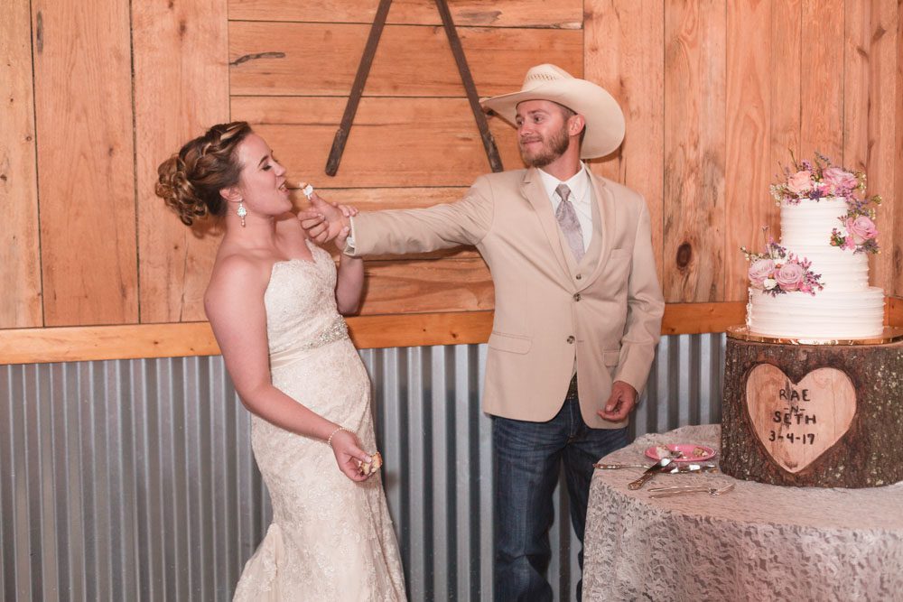 Newlyweds share their first slice of cake by smashing it in each others faces during their barn wedding in Central Florida