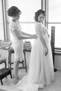 Black and white photography of Bride getting into her wedding dress with her mom during her Kissimmee wedding day