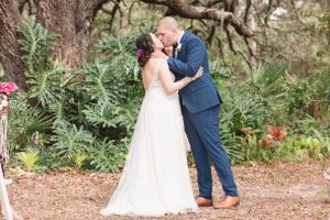 Top Orlando wedding photographer captures bride and groom sharing their first kiss under a tree during their outdoor wedding ceremony in Orlando Florida