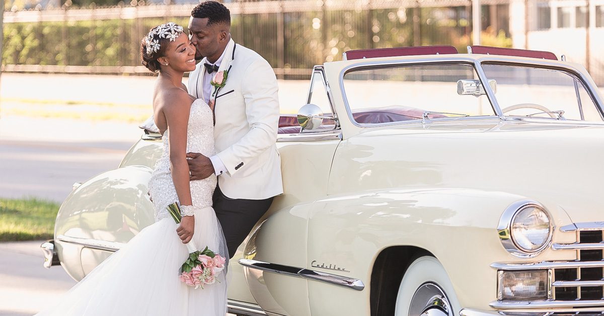 Couples poses in front of an antique vintage car during their Orlando wedding at Lake Eola captured by top wedding photographer and videographer