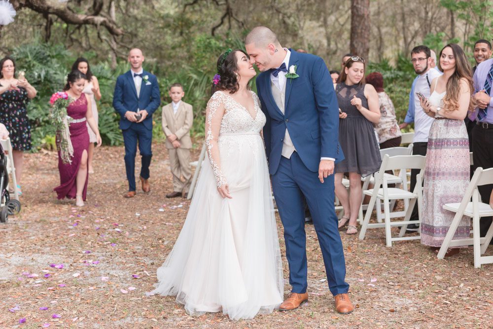 Newlyweds kiss during their outdoor wedding ceremony under a tree during their Central Florida wedding day
