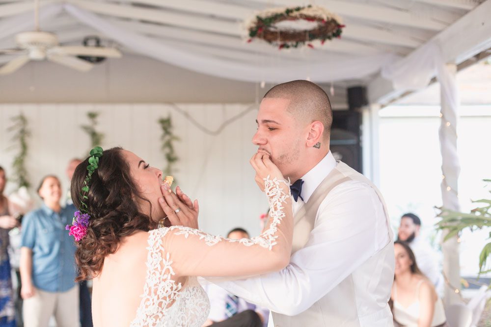 Bride and groom cut the cake and smash it in each others face during a fun outdoor wedding in Orlando, Florida