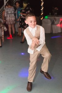 Fun action shot on the dance floor photo of the ring bearer during the reception at an intimate wedding day in Kissimmee captured by top Orlando wedding photographer