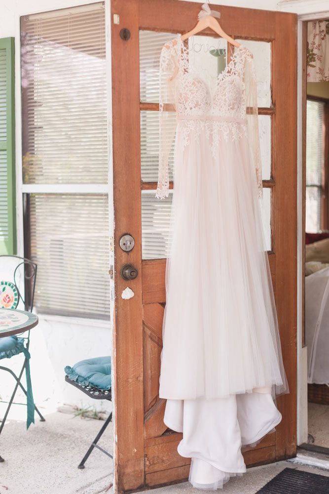 Bride's wedding dress hanging on a rustic door for her intimate Orlando wedding day