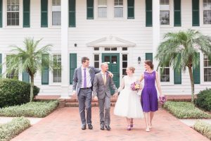 Orlando wedding photographer captures a fun portrait of the bride and groom with their wedding party in front of the Cypress Grove Estate House venue in Orlando