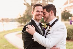 Portrait of two grooms at their gay wedding at sunset by the water in Orlando Florida