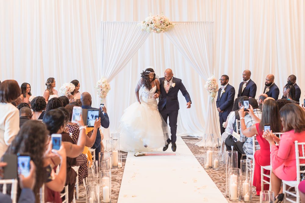 Newlyweds jump the broom as husband and wife during their indoor wedding ceremony in Orlando at the Four Seasons