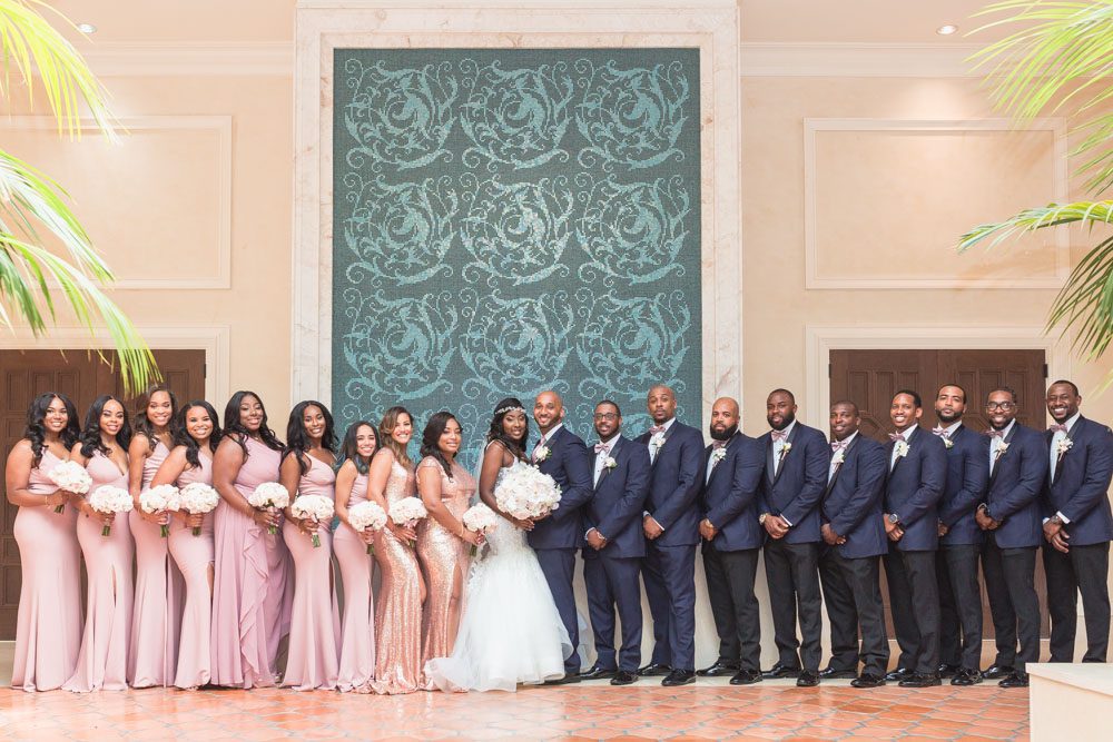 Photo of the entire bridal party featuring bridesmaids in pink and sequin dresses and groomsmen in blue suits at the Four Seasons