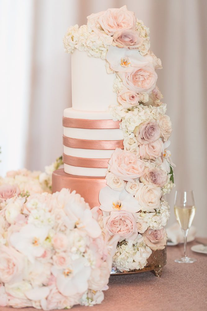 Orlando wedding photographer captures close up photo of gold and white wedding cake with flowers at the Four Seasons