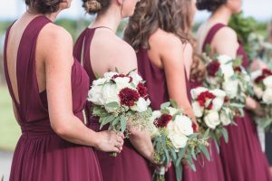 Orlando wedding photographer captures outdoor ceremony featuring burgundy red dresses and wine colored floral bouquets