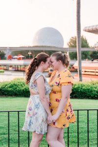 Same-sex couple in front of spaceship earth at Epcot in Disney during their engagement session with top Orlando gay wedding photographer