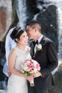 Candid portrait of the bride and groom at Myriad Gardens in front of a waterfall in Oklahoma City captured by traveling photographers from Orlando