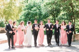 Top Orlando wedding photographers capture sunny photo of a wedding party wearing pink dresses at Myriad Gardens in Oklahoma City