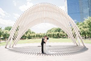 Portrait of the bride and groom in front of a sculpture at Myriad Gardens in Oklahoma City captured by traveling photographers