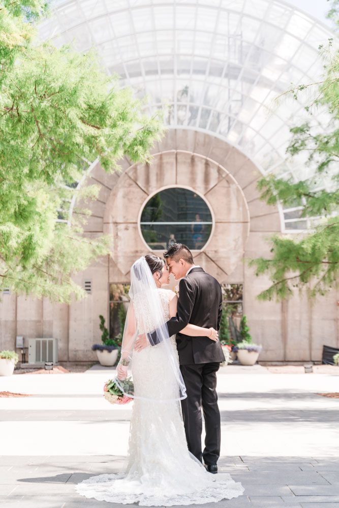 Portrait of the bride and groom in front of a building at Myriad Gardens in Oklahoma City captured by traveling photographers