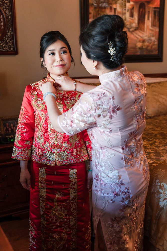 Brides mom helps her with traditional chinese wedding attire during her Asian wedding in Oklahoma City