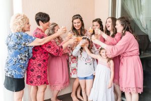 Bride and bridesmaid toast in matching robes during getting ready part of the wedding day in Orlando