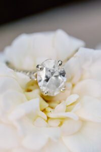 Close up of oval engagement ring on a white rose during Disney photo shoot in Orlando