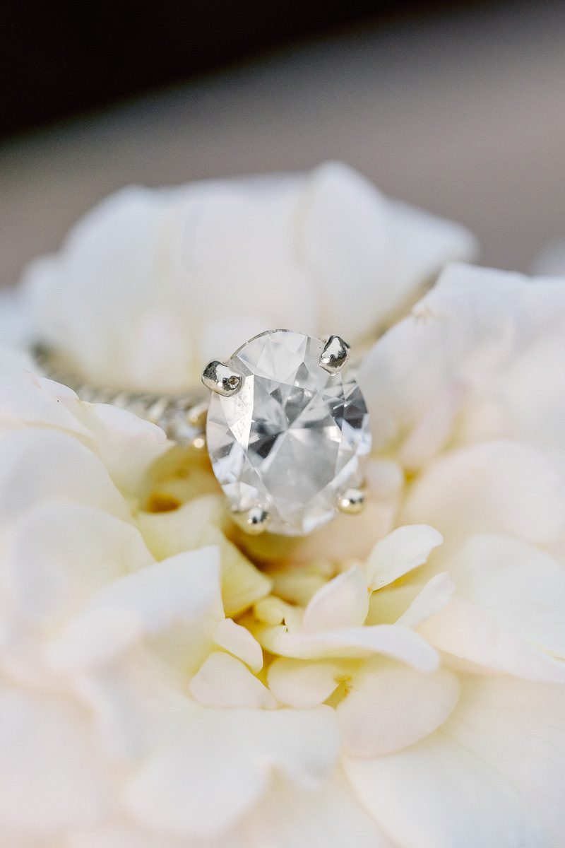 Close up of oval engagement ring on a white rose during Disney photo shoot in Orlando