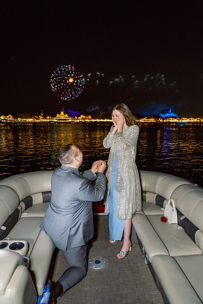 Disney world surprise engagement during fireworks captured by top Orlando proposal photographer on pontoon boat cruise