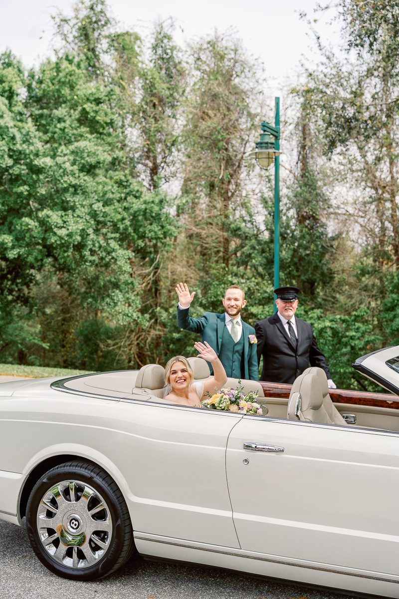 Couple leaving Disney wedding photography at Boardwalk Inn with luxury Bentley convertible car captured by top Orlando wedding photographer & videographer