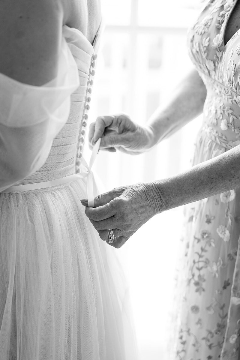 Black and white photo of mom putting dress on bride at Disney wedding in Orlando Florida