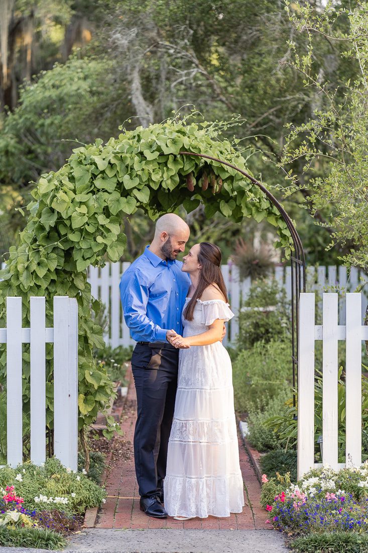 Orlando engagement photographer captures a romantic photoshoot at Leu Gardens with a white picket fence and lush greenery