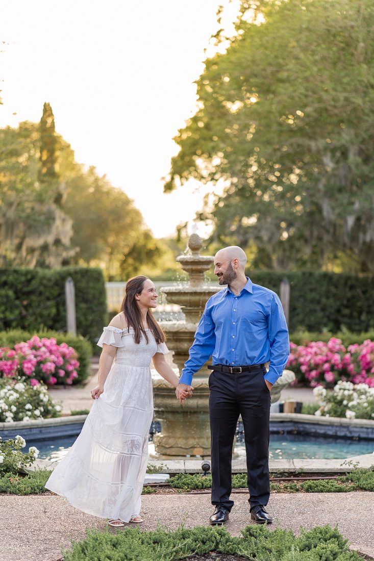 Orlando engagement photographer captures a romantic photoshoot at Leu Gardens with a water fountain, blooming flowers and lush greenery