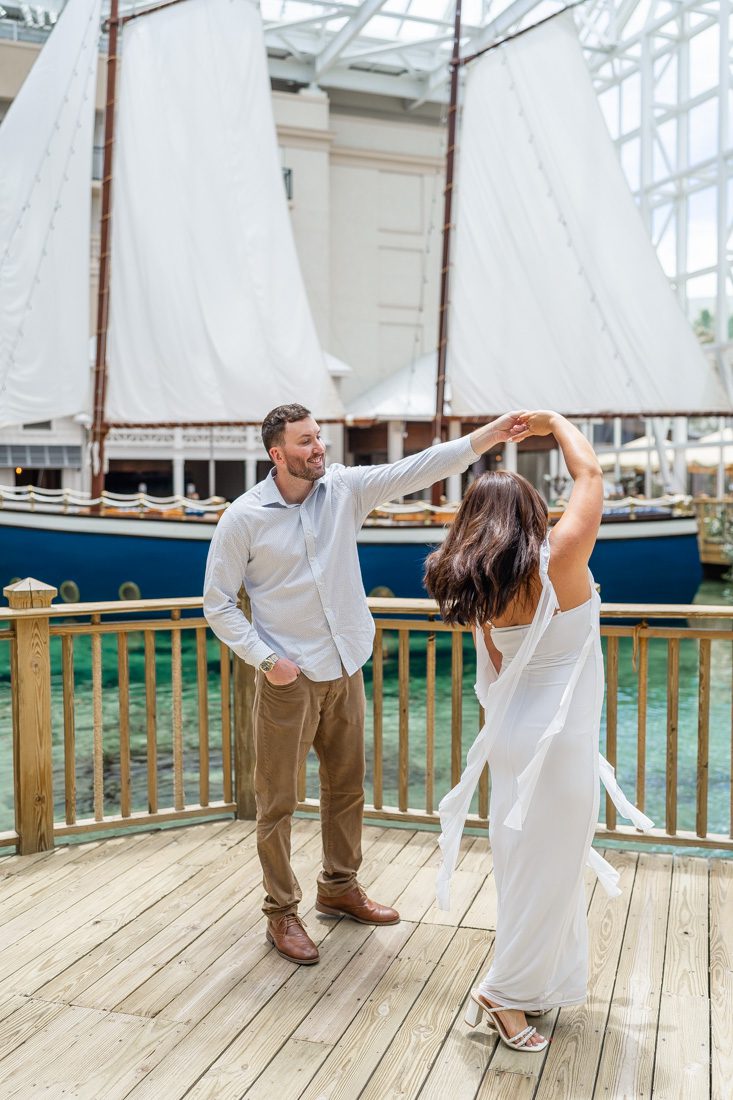 Fun dancing photo in front of a sailboat at Gaylord Palms Kissimmee indoor atrium with top rated photographer