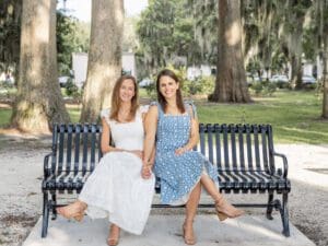 Beautiful couple sitting on black bench in Kraft Azalea Park during golden hour. Captured by top wedding photographer in Orlando