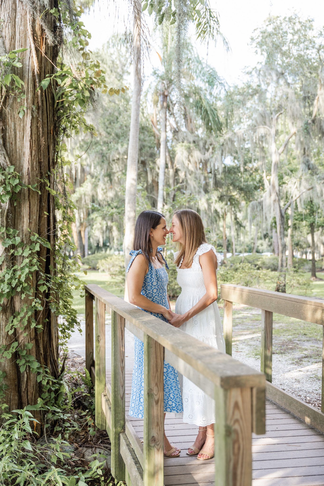 Couple smiling and holding hands on a wooden bridge surrounded in Kraft Azalea Park, Top Orlando Wedding Photographer