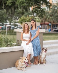 Same sex couple cuddling with their happy dogs on a sunny day at Kraft Azalea Park by Top Orlando Wedding Photographer