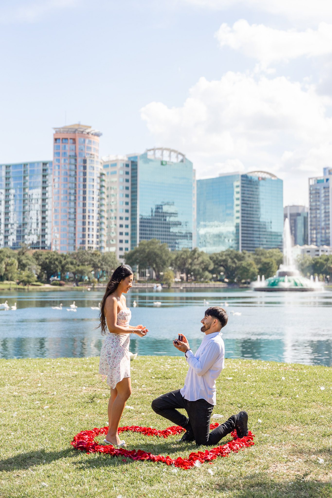 Orlando proposal photographer captures a surprise proposal at Lake Eola with red rose petals and the iconic fountain in downtown Orlando.