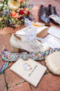 Wedding detail photo featuring handfasting cord, matching rings, vow books, and heirloom pearls.