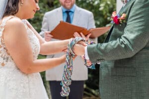 Bride and groom participating in a handfasting ceremony while tying the knot.