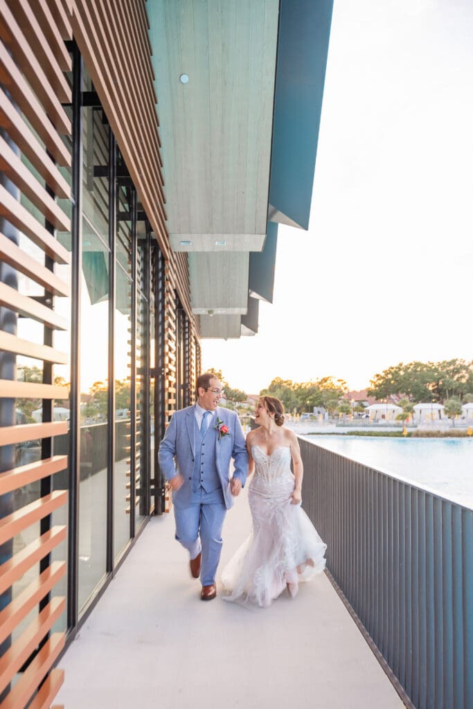 Newlyweds run hand in hand along the waterfront at Evermore Resort in Orlando, beautifully photographed Captured by Elle, Premier Wedding photographer & videographer.