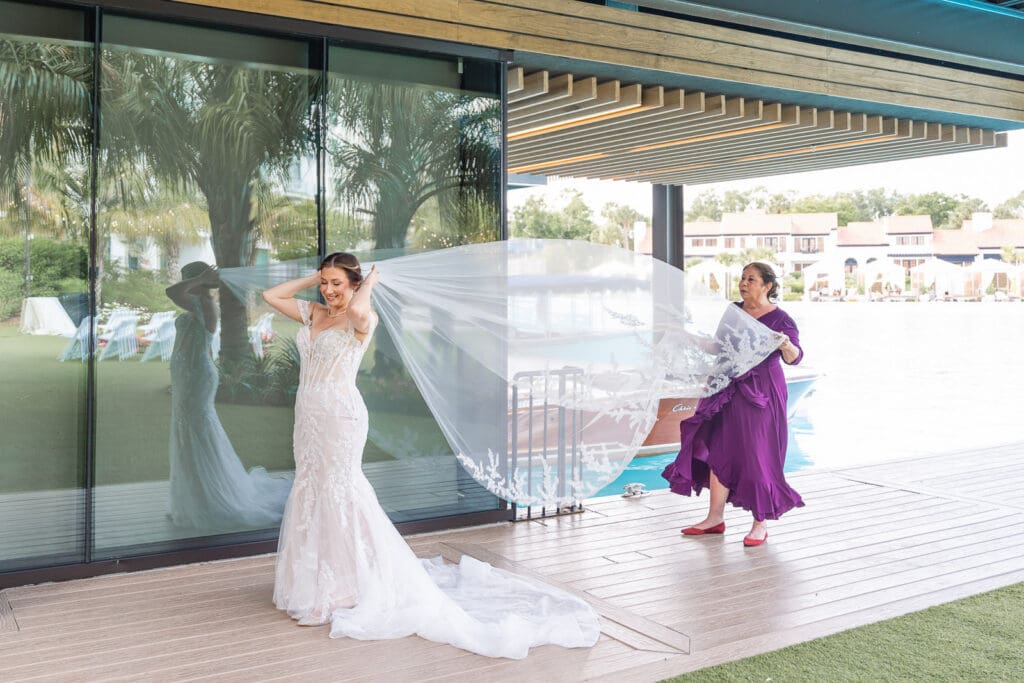 Bride's veil preparation overlooking Evermore Resort's waterfront in Orlando, captured by luxury wedding photographer & videographer Captured by Elle